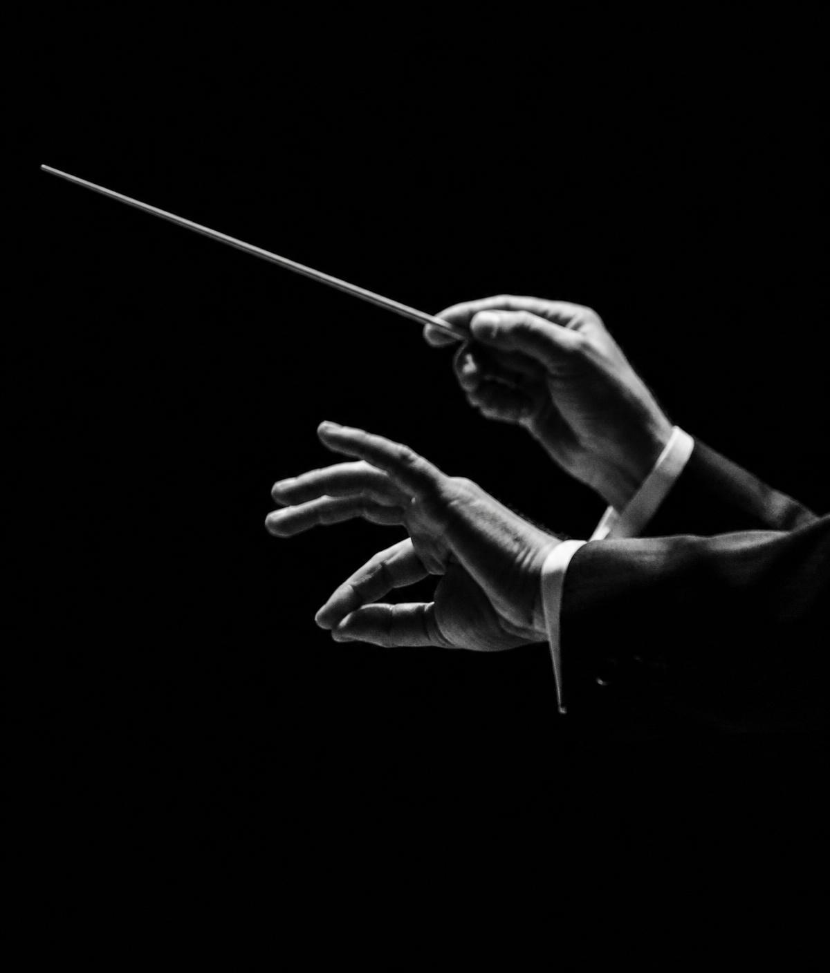 Mãos de um maestro conduzindo com a batuta